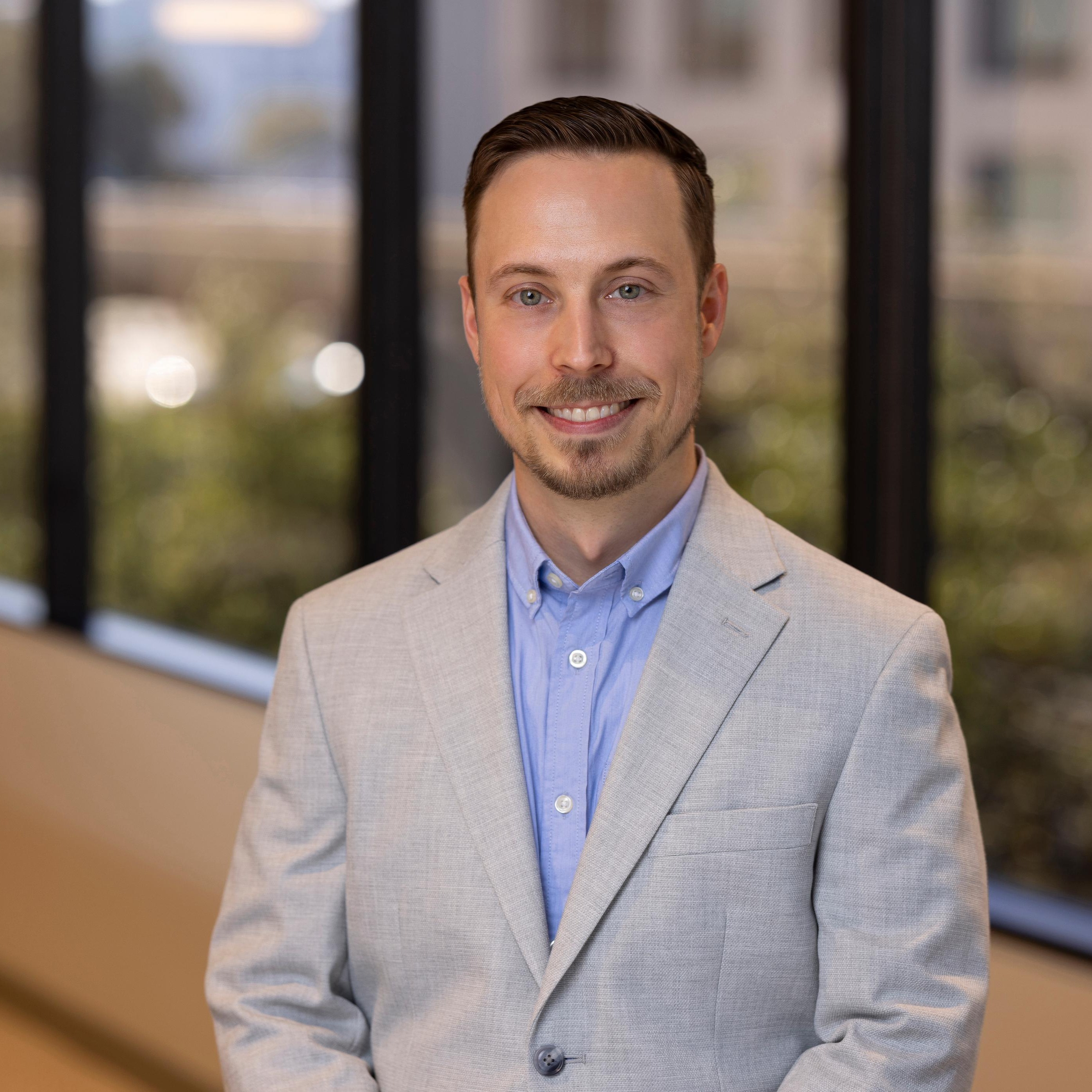 Bryan Grohman, Senior Director, Data Science Engineering at Post Acute Analytics, in a light gray blazer and blue shirt in a modern office