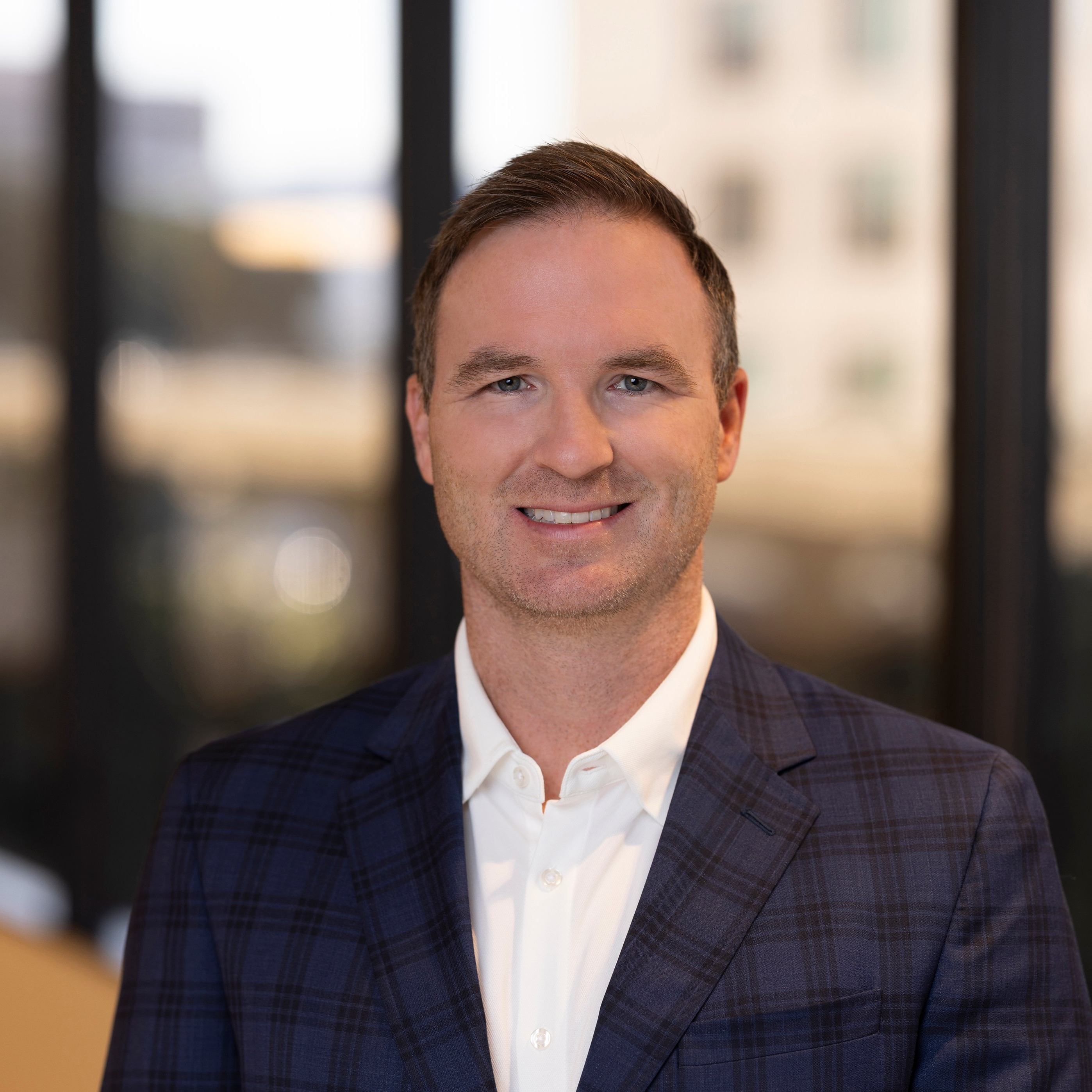 Daniel Berry, VP, Operations at Post Acute Analytics, in a navy plaid blazer and white shirt in a modern office