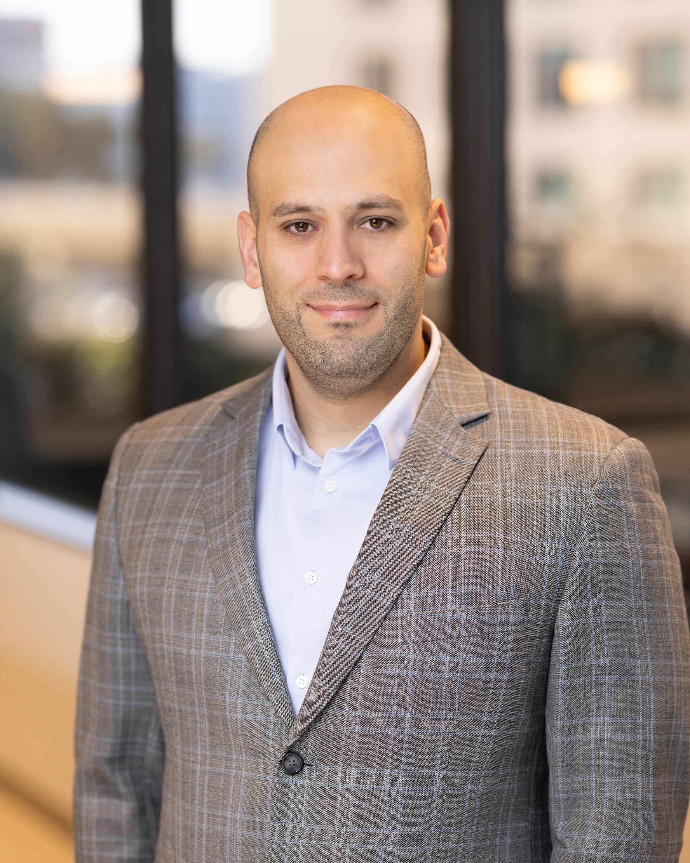 Fadi Almachraki, Chief Technology Officer of Post Acute Analytics, in a gray checked blazer and light shirt in a modern office