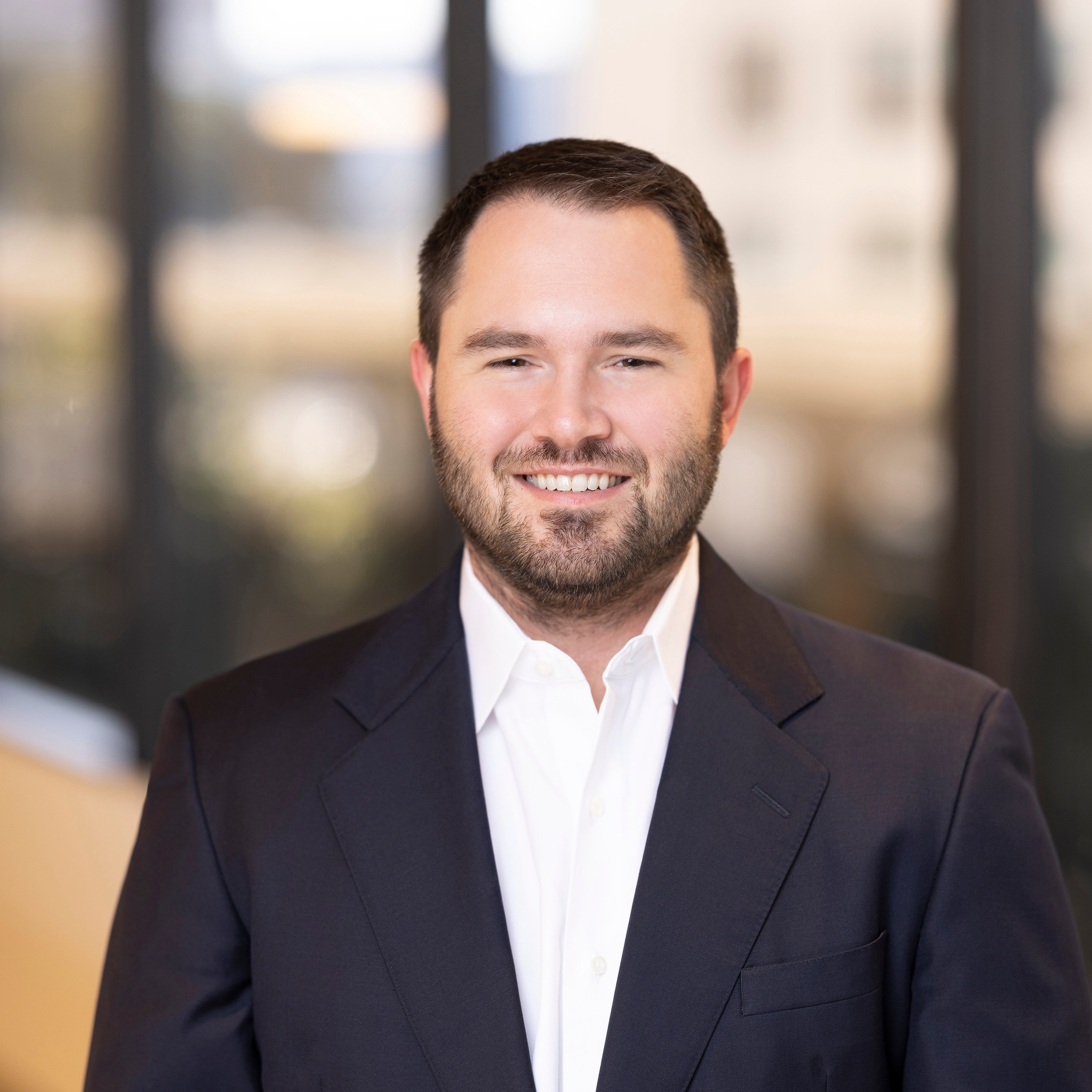 Harrison Brown, VP, Engineering & Analytics at Post Acute Analytics, in a navy suit and white shirt in a modern office
