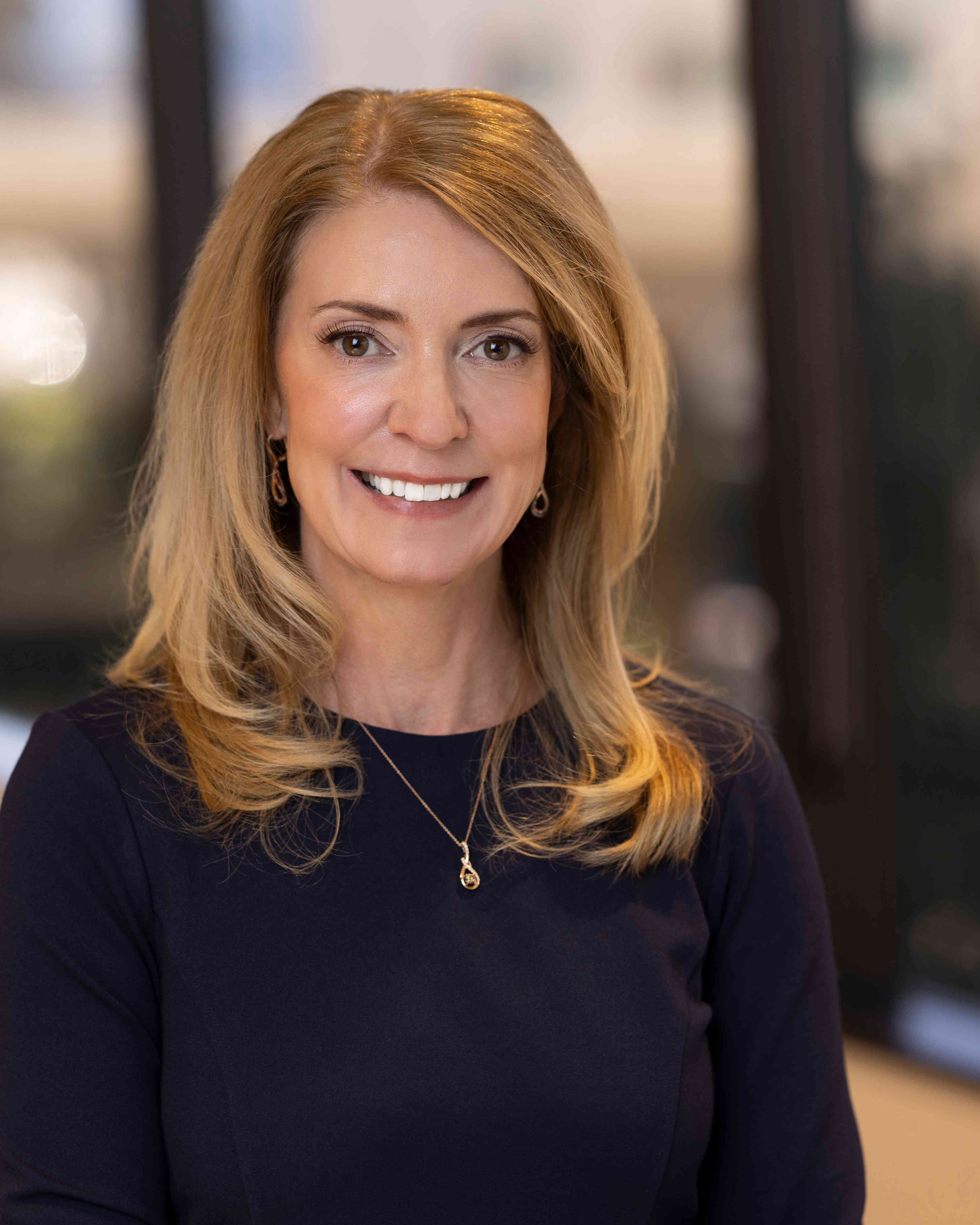 Jennifer Terrell, MD, Chief Medical Officer of Post Acute Analytics, in a navy top in a modern office