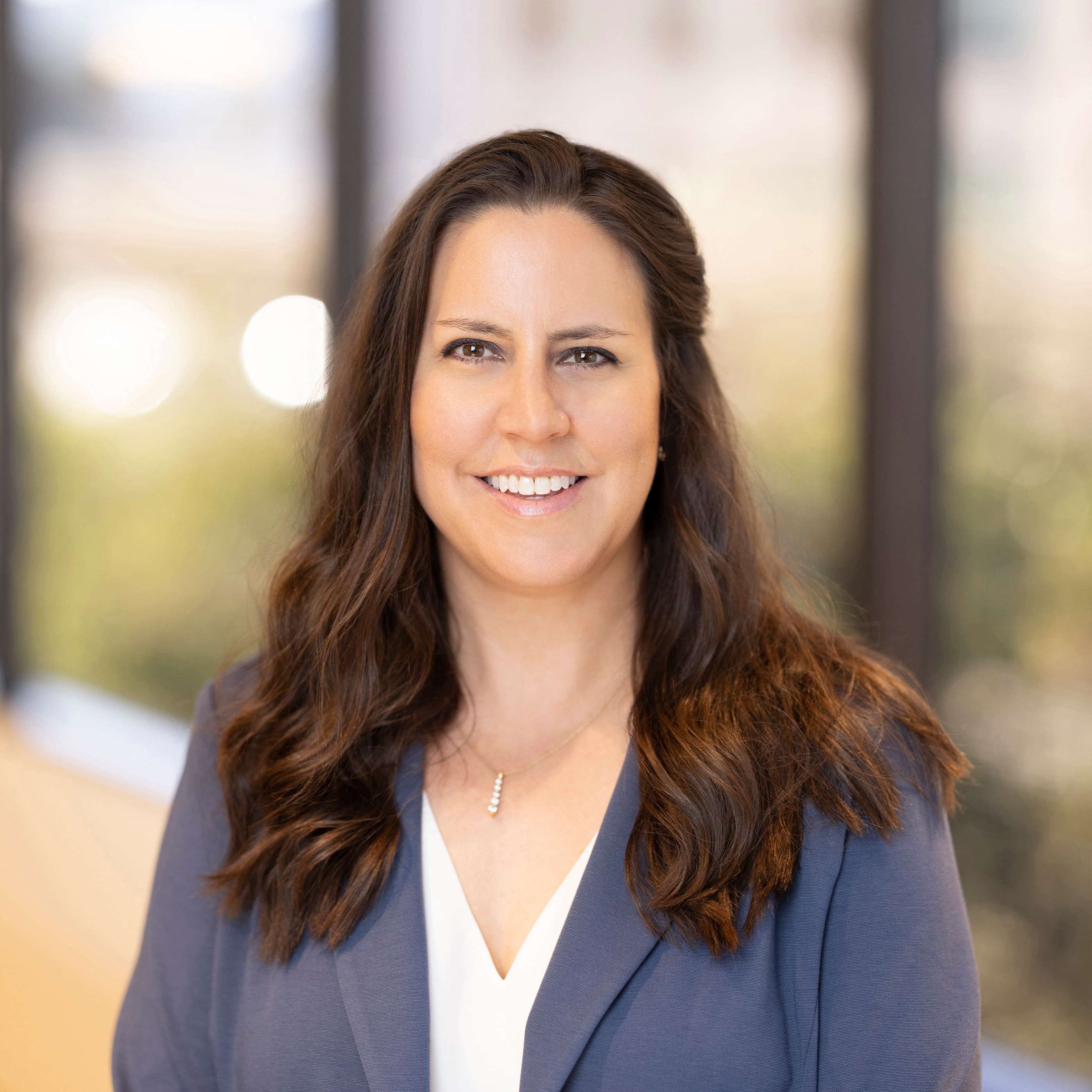 Julie Meurer, Director, Implementations - Project Management at Post Acute Analytics, in a slate-blue blazer and white top in a modern office