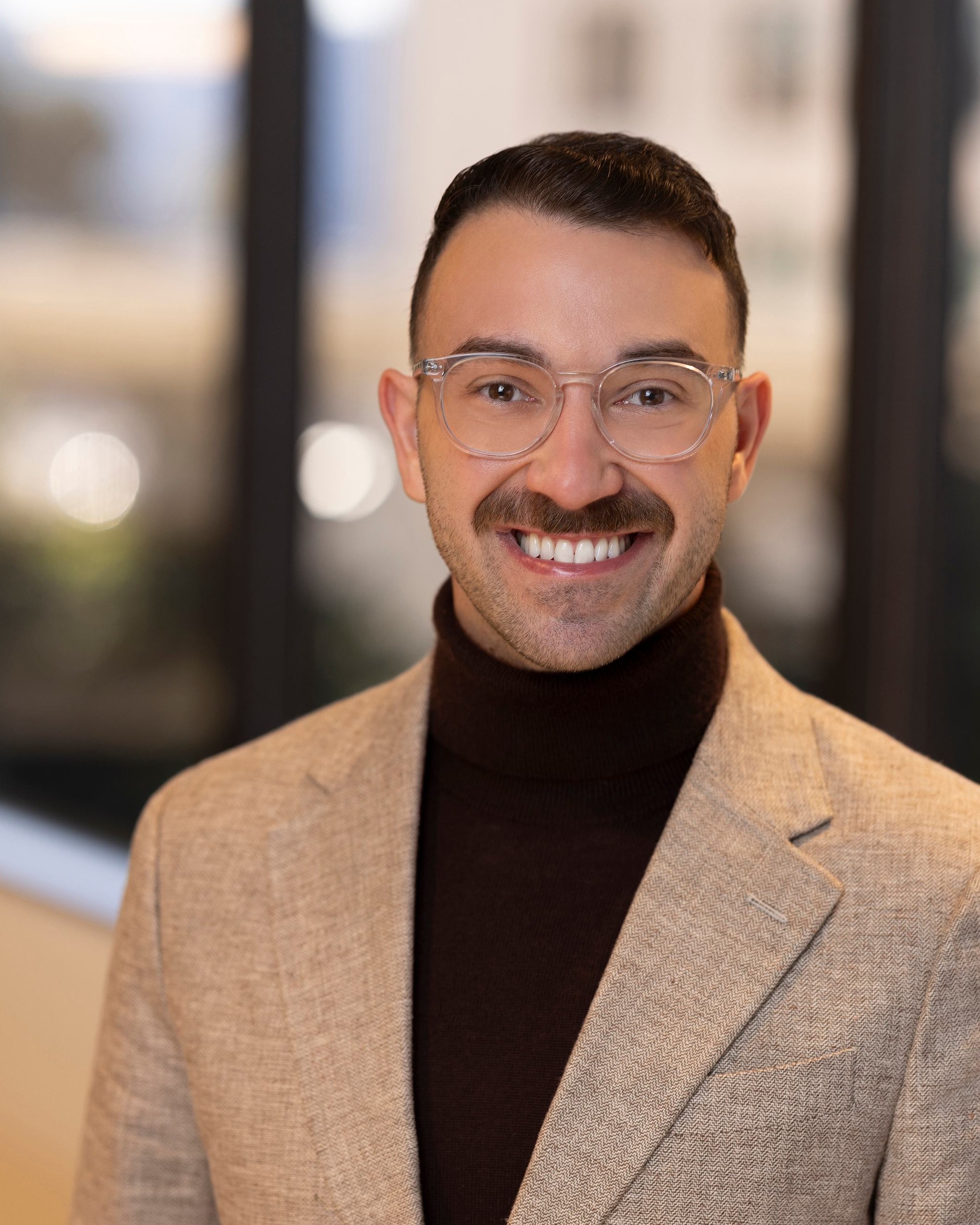 Keaton West, Chief Clinical Officer of Post Acute Analytics, in a tan blazer and dark turtleneck in a modern office