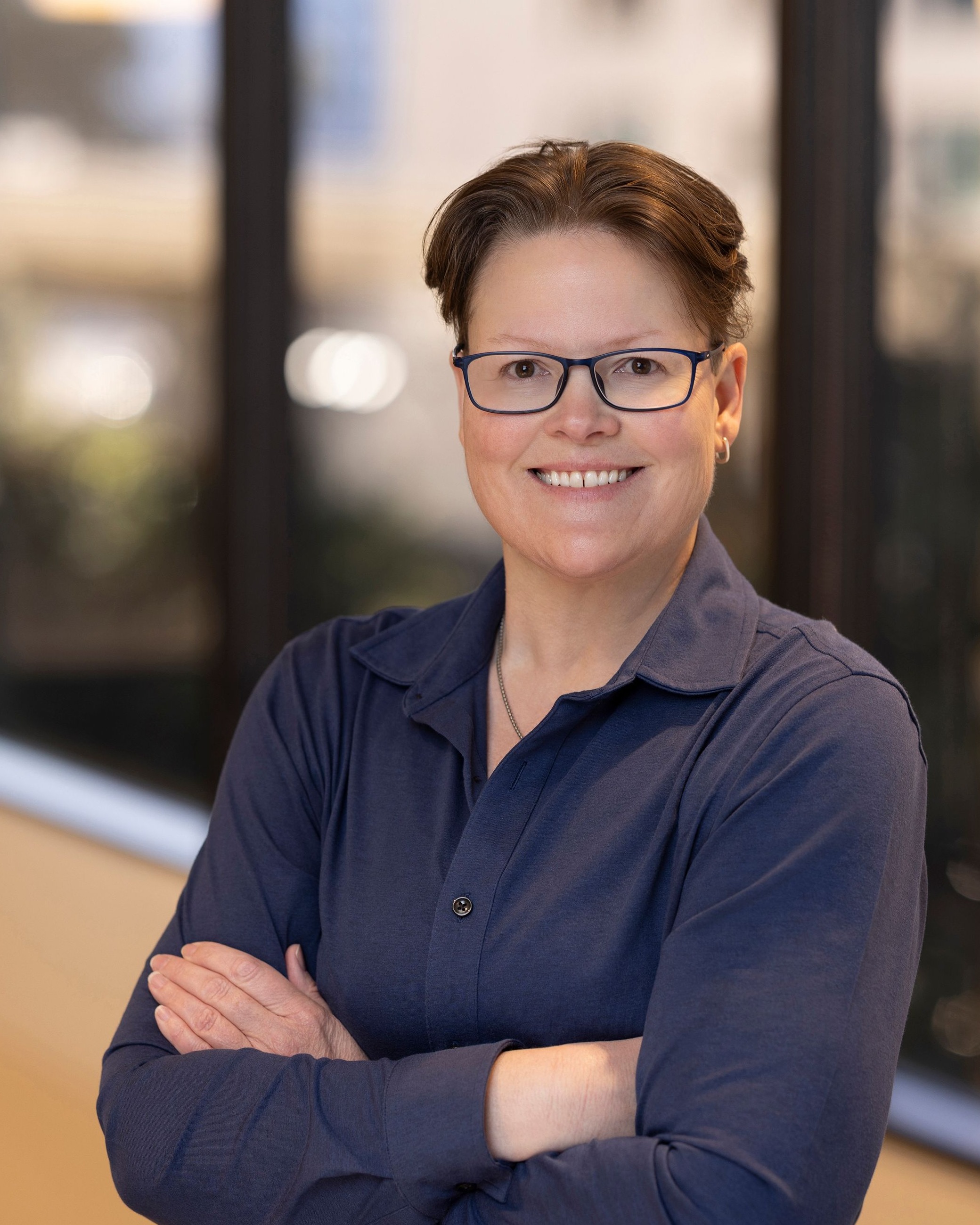 Laura Evans, Chief Information Security Officer of Post Acute Analytics, in a navy shirt and glasses in a modern office