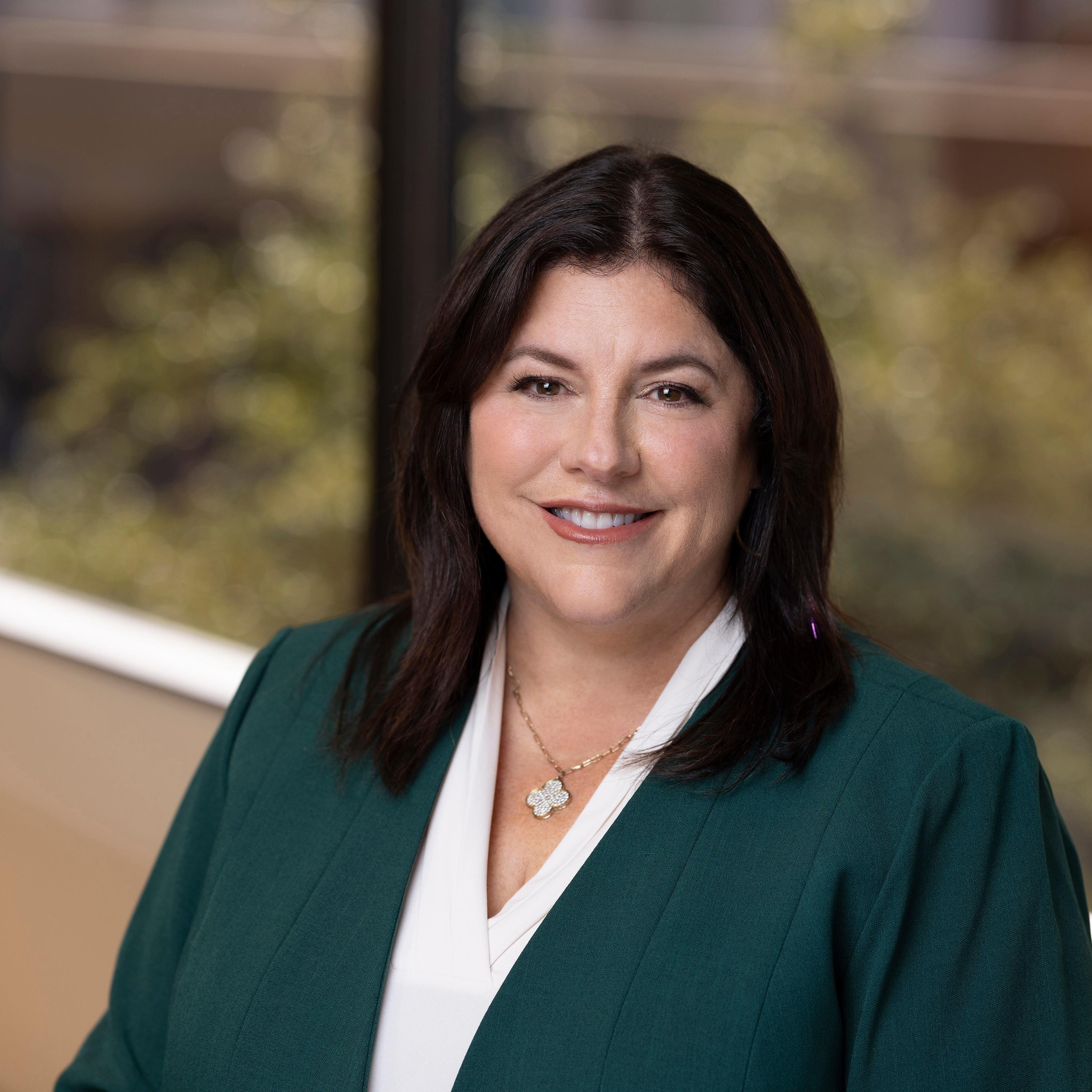 Lynn Mueller, SVP, Growth at Post Acute Analytics, in a dark green blazer and white top in a modern office