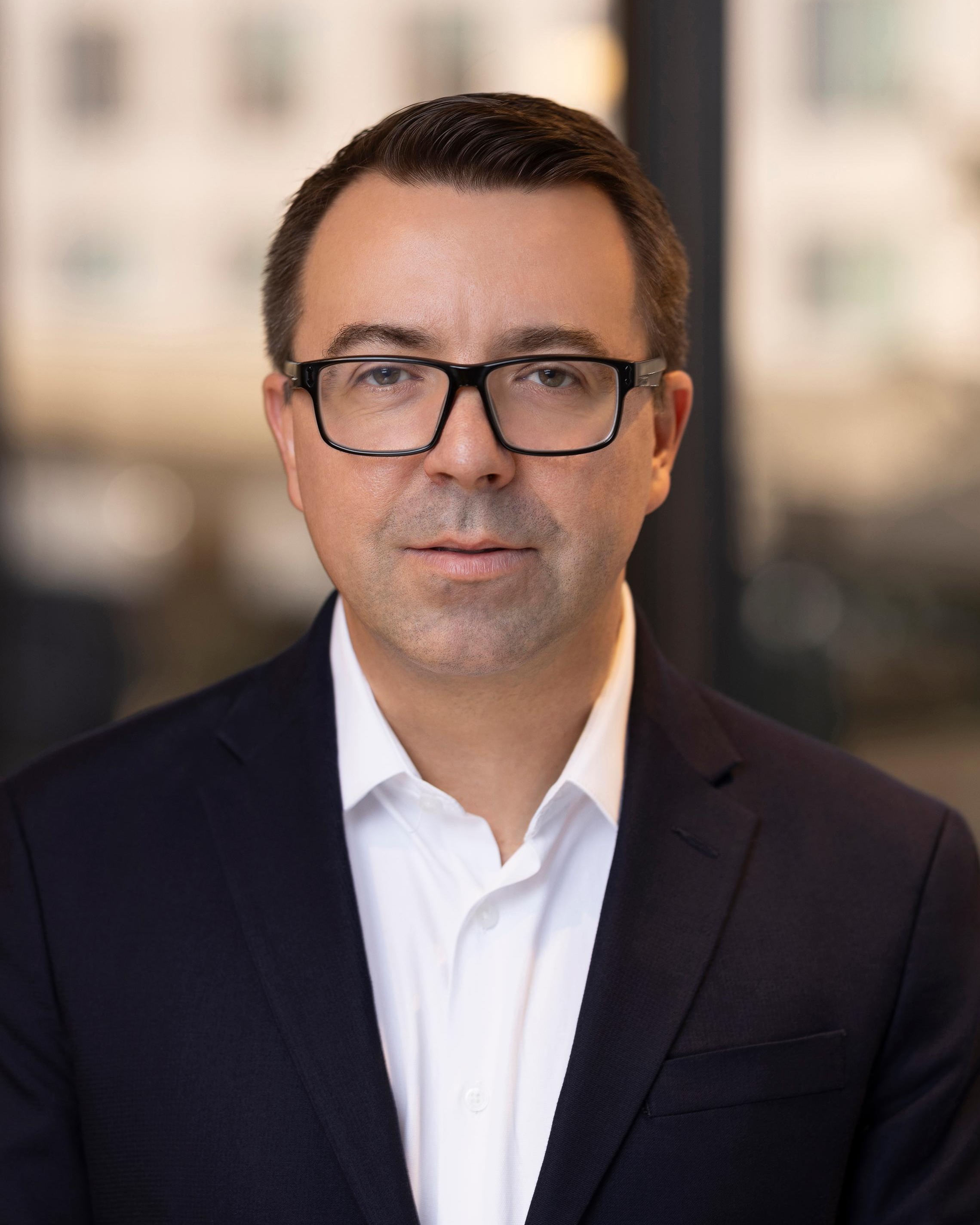 Paul Martinchuk, Chief Financial Officer of Post Acute Analytics, in a navy suit and white shirt in a modern office