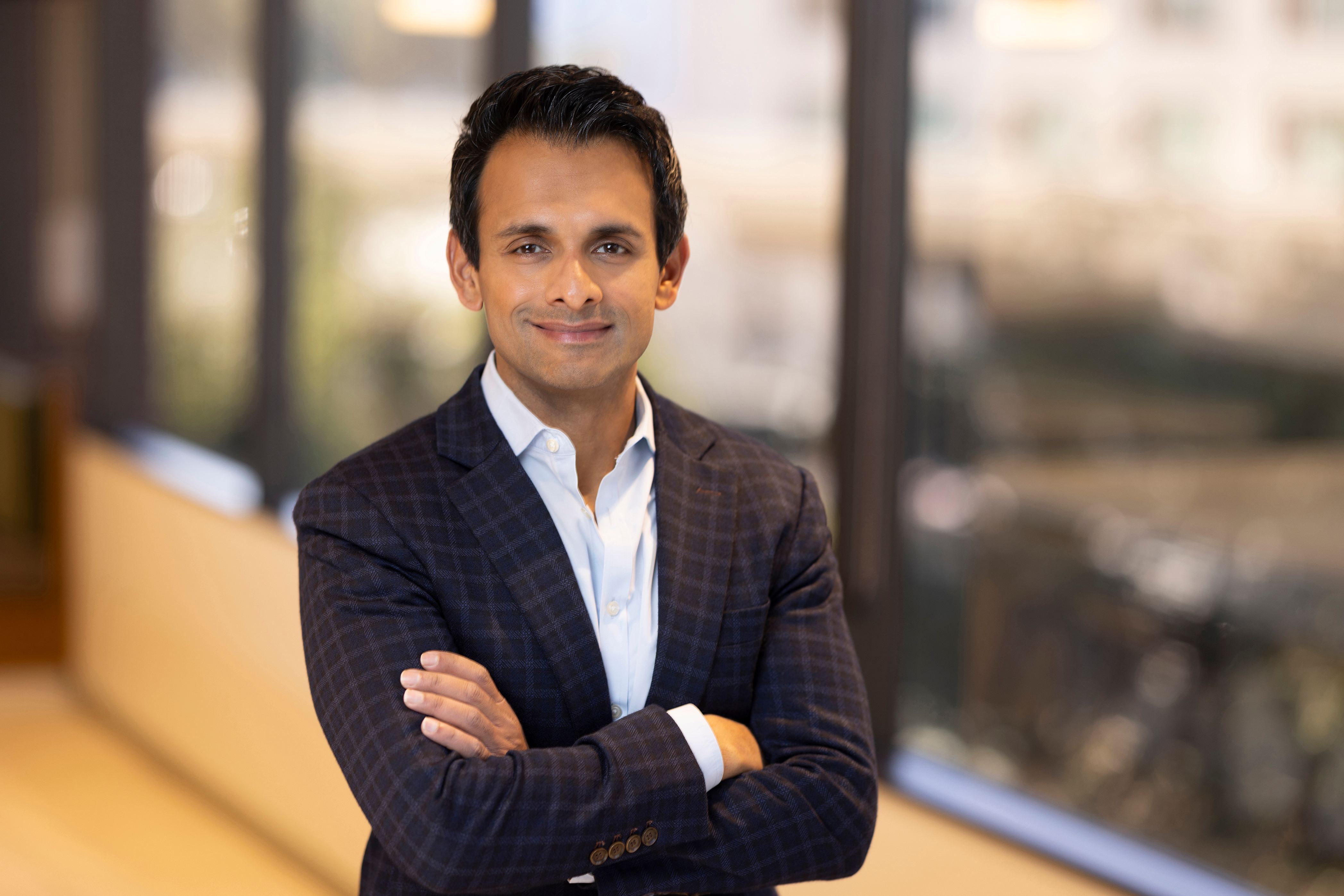 Saqib Akhter, Chief Executive Officer of Post Acute Analytics, in a navy blazer with arms folded in a modern office